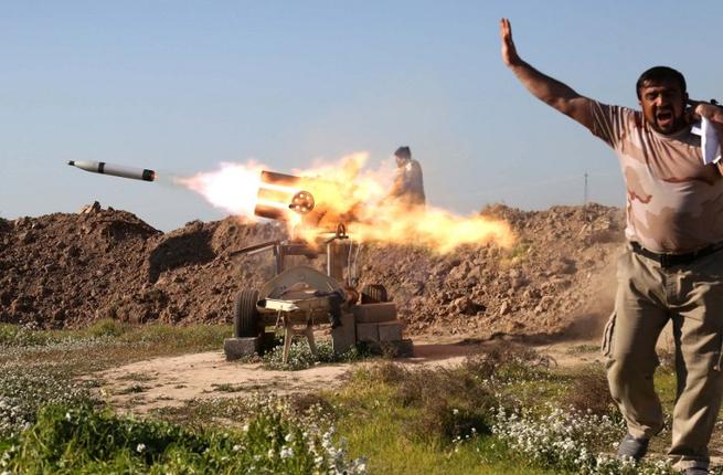 مقاتل من قوات الحشد الشعبي الشيعية يغطي اذنه اثناء اطلاق صاروخ في بلدة طوز خرماتو جنوب مدينة كركوك العراقية. 