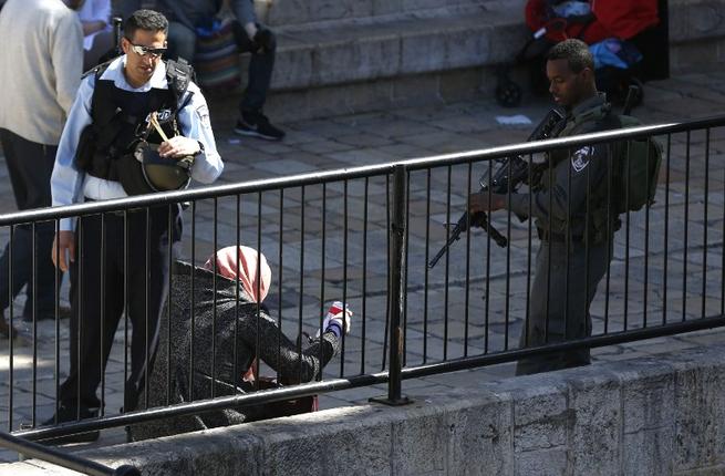 شرطي اسرائيلي يطلب من فتاة فلسطينية بطاقة هويتها امام بوابة دمشق في القدس الشرقية، بينما يصوب جندي فوهة بندقيته باتجاه الفتاة. 