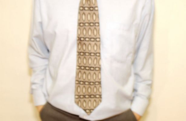 Businessman in tie leaning against wall.jpg