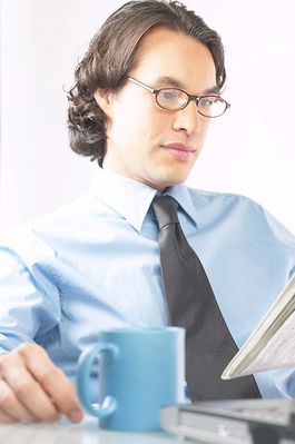 Businessman reading newspaper at his desk 100.jpg