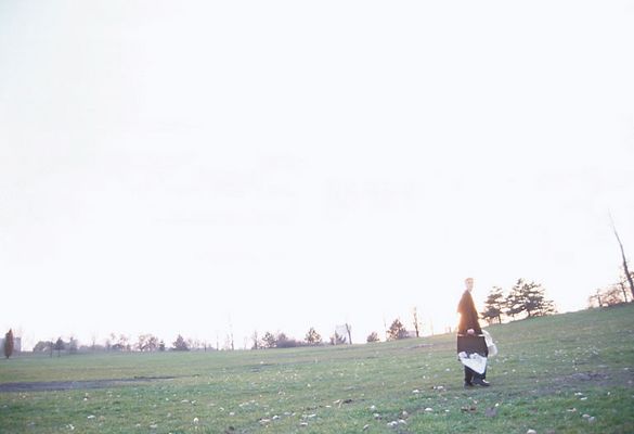 Businessman walking through field with briefcase and newspaper.jpg