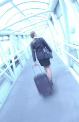 Businesswoman pulling suitcase through glass hallway uid 1284391.jpg