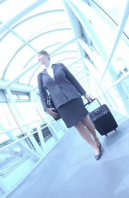 Businesswoman pulling suitcase through glass hallway uid 1284392.jpg