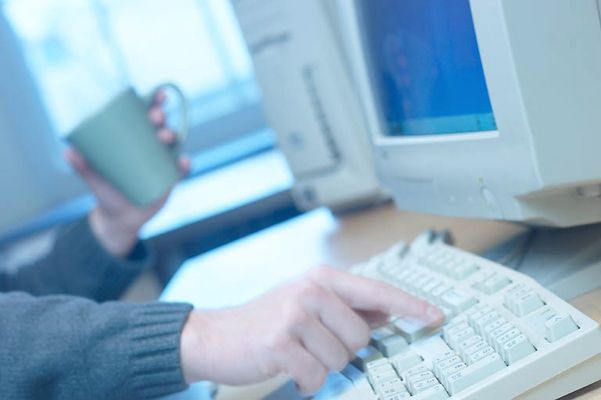 Caucasian man typing on computer keyboard while drinking coffee.jpg
