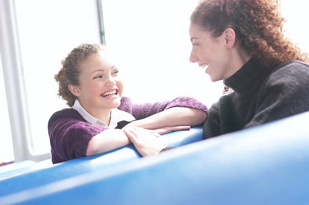 Two smiling women sitting in blue vinyl seats uid 1283663.jpg