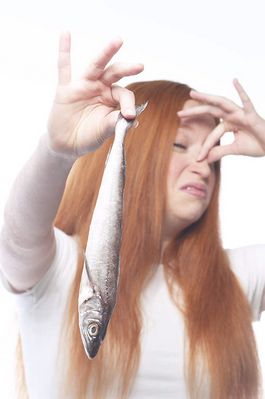 Woman holding fish and plugging nose.jpg