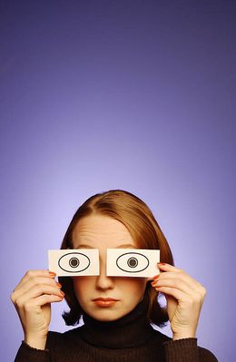 Woman holding paper eyes over her face.jpg