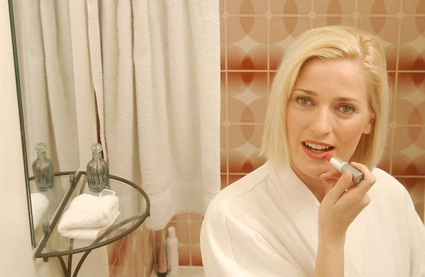 Woman putting on lipstick in bathroom mirror.jpg