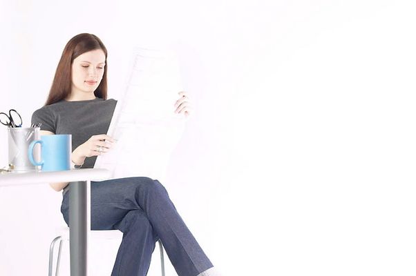 Woman sitting and reading newspaper at desk.jpg