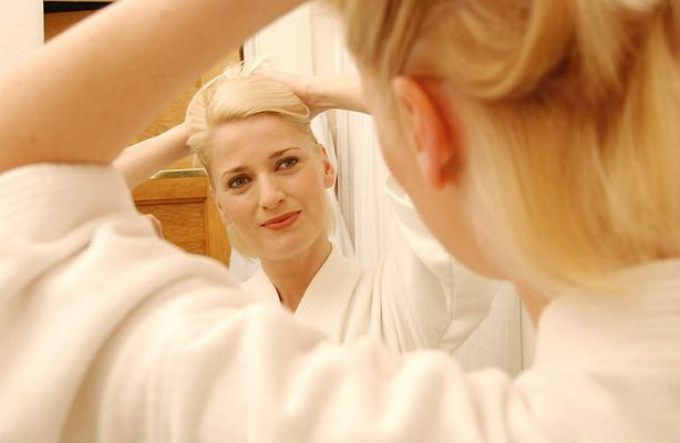 Woman trying hairstyle in bathroom mirror.jpg