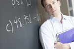 Math teacher at blackboard holding textbook.jpg