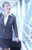 Smiling businesswoman with luggage in glass hallway.jpg