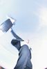 View of businessman throwing briefcase against blue sky.jpg