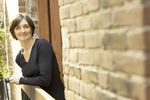 Woman leaning on balcony of brick building.jpg
