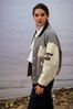 Woman wearing letterman jacket beside lake.jpg