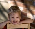 Young boy sitting backwards on a chair and smiling.jpg
